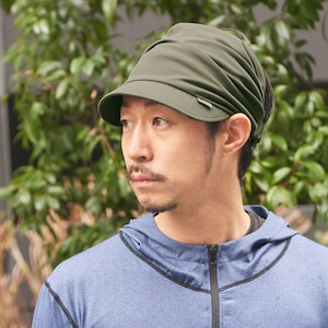 May include: A person wearing a blue hooded sweatshirt with a black zip and a small logo on the left chest. They are also wearing a green visor hat with a black brim.