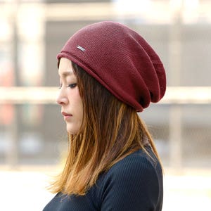 Japanese female model with brown ombre sholder length hair wearing a burgundy 100% silk slouchy beanie for men and women, black shirt during summer, slouchy summer beanie