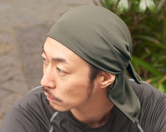 Könnte beinhalten: Eine Person trägt einen dunkelgrünen Kopftuch im Bandanastil mit einem dunkelgrauen Langarmshirt.