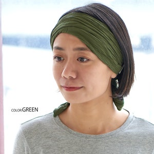 May include: A green fabric headband worn by a person with short dark hair. The headband is tied in a knot at the back of the head.  COLOR: GREEN
