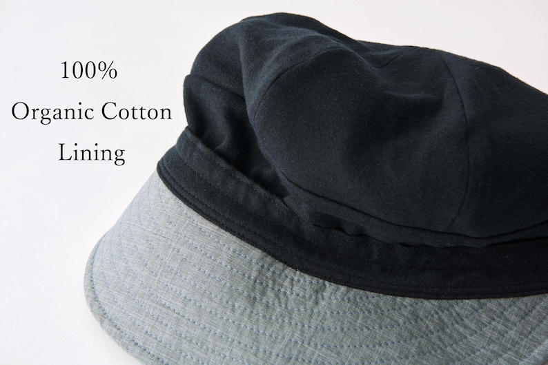 May include: A black hat with a grey brim. The hat has a dark lining and the text "100% Organic Cotton Lining". The hat is made of a soft material and is likely for sun protection.