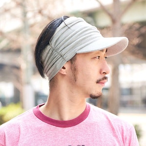 Summer time, Japanese male model with black hair wearing a light grey sun visor sun hat with side scrunch design and front that stretches to the top of the head, dark, white visor, sun hat for men and women