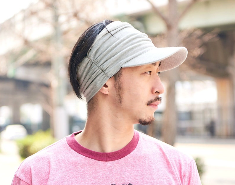 Summer time, Japanese male model with black hair wearing a light grey sun visor sun hat with side scrunch design and front that stretches to the top of the head, dark, white visor, sun hat for men and women