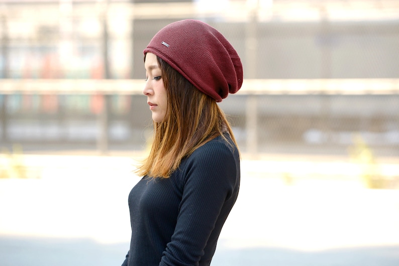 Japanese female model with brown ombre sholder length hair wearing a burgundy 100% silk slouchy beanie for men and women, black shirt during summer, slouchy summer beanie