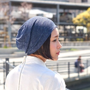 Japanese female model with black hair in a short bob wearing a white top and a navy 100% linen eco friendly hat, a beanie with a very slight slouch on a summer day