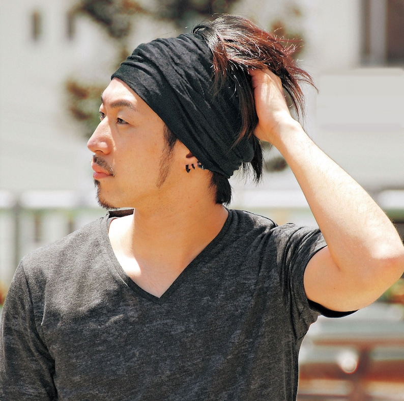 May include: A man wearing a black headband and a dark gray v-neck t-shirt.