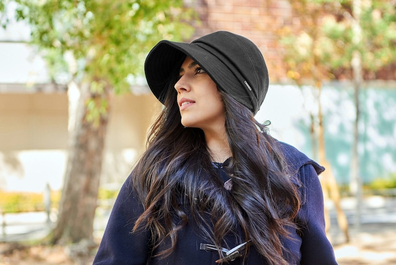 Mexican woman wearing a black autumns and winter sun hat with an extra wide brim that stretches from ear to ear on a fall afternoon.