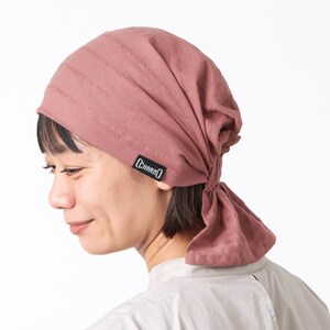K&ouml;nnte beinhalten: Ein staubiges rosafarbenes Baumwollbandana mit einem schwarzen "CHARM'D"-Logo. Das Bandana ist am Hinterkopf zu einem Knoten gebunden.