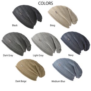 May include: A collection of seven slouchy beanies in various colors including black, beige, dark gray, light gray, navy, dark beige, and medium blue. Each beanie features a textured knit pattern and a small rectangular metal tag on the side.