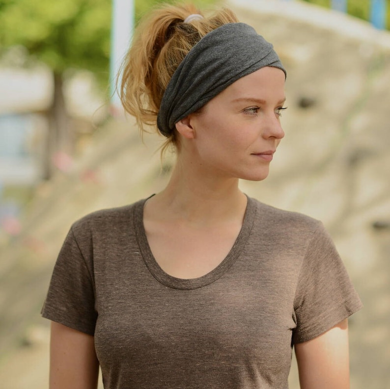 May include: A woman wearing a gray t-shirt and a gray headband.