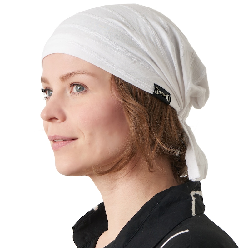 K&ouml;nnte beinhalten: Ein wei&szlig;es Baumwollbandana mit einem schwarzen CHARM-Band. Das Bandana ist um den Kopf gebunden und hat einen langen Schwanz, der am R&uuml;cken herunterh&auml;ngt.