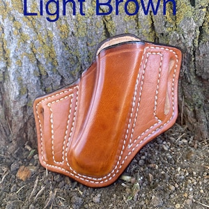 May include: Light brown leather holster with white stitching. The holster is designed to hold a small pocket knife or other similar tool.