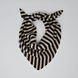 May include: A black and cream striped knitted scarf with a triangular shape.