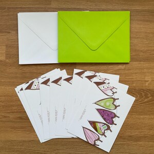 Peut inclure: Un ensemble de papeterie comprenant des enveloppes blanches et vertes, ainsi que plusieurs cartes avec un motif de papillon. Les cartes présentent un motif répété de formes de papillons colorés et le texte "a little note..." imprimé.