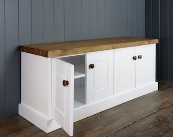 May include: White wooden cabinet with a natural wood top and three doors. The cabinet has a shelf inside and a single door is open.