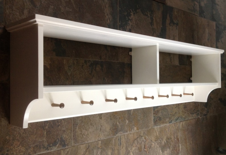 Coat rack with pegs to hang coats. Display / storage shelf divided into two compartments. Painted white.