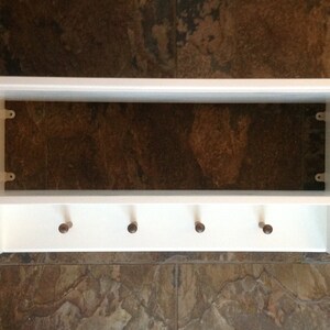 Puede incluir: Estante de madera blanca con cinco ganchos en la parte inferior. El estante tiene un dise&ntilde;o sencillo y es perfecto para un pasillo o una entrada.