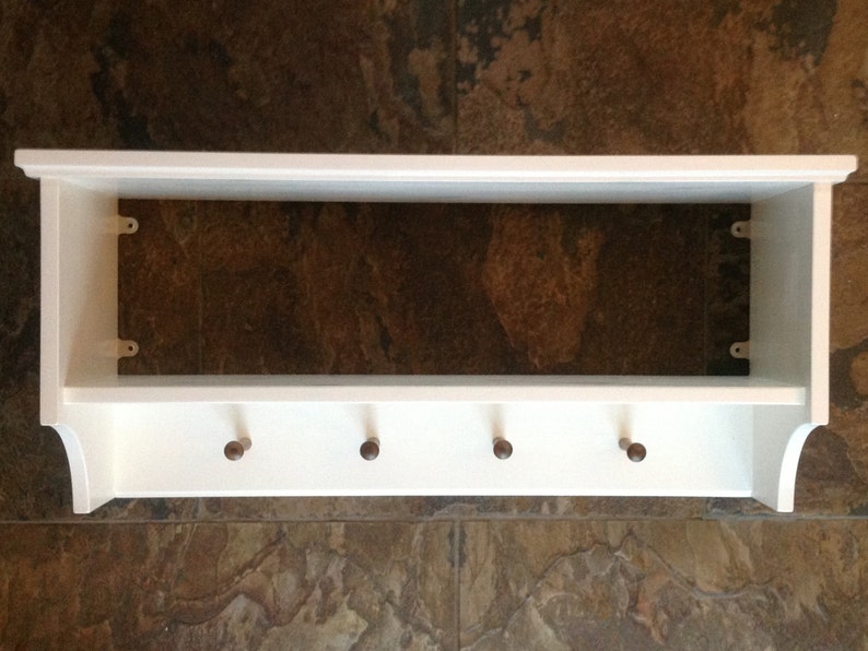 Puede incluir: Estante de madera blanca con cinco ganchos en la parte inferior. El estante tiene un dise&ntilde;o sencillo y es perfecto para un pasillo o una entrada.
