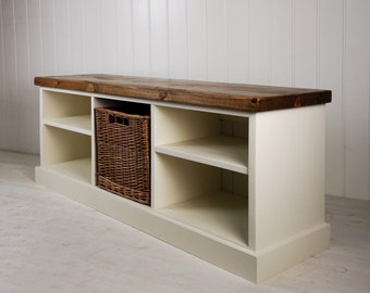 May include: White wooden bench with a brown wood top and three shelves. A wicker basket is on the bottom shelf.