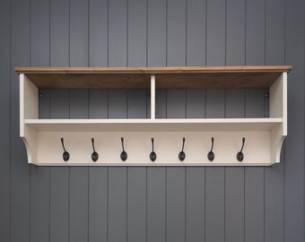 May include: White wooden coat rack with a brown top shelf and eight black metal hooks.