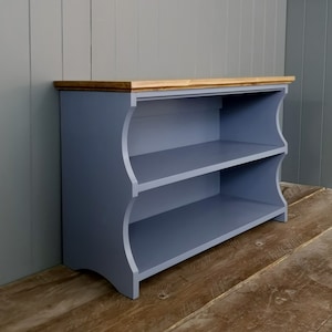 May include: A two-tiered shoe rack with a light blue finish and a natural wood top. The shelves have a curved front edge and the base has a slight curve.