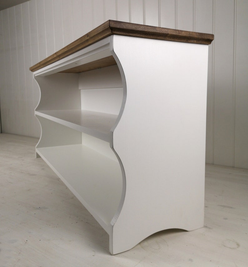 May include: White wooden shoe rack with two shelves and a brown stained top. The shoe rack has a curved design and is freestanding.