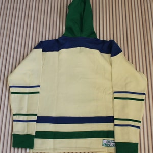 May include: A yellow, green, and blue striped hoodie with a green hood. The hoodie has a small patch on the bottom right side that says "State Street Third Ave."