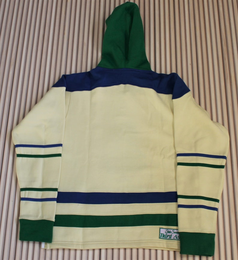 May include: A yellow, green, and blue striped hoodie with a green hood. The hoodie has a small patch on the bottom right side that says "State Street Third Ave."
