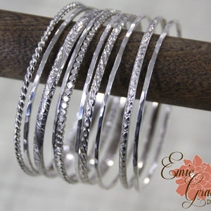 Conjunto de dez pulseiras de prata esterlina, com pingentes, bolinhas, florais, torcidos, trançados, folhas e finos martelados.