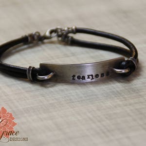 May include: A black leather bracelet with a silver metal tag that says "fearless".
