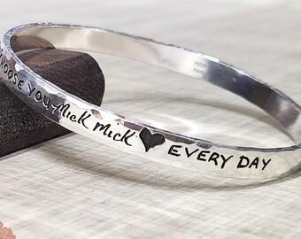 May include: Silver bangle bracelet with the words "Choose you first" and a heart symbol followed by the words "every day".