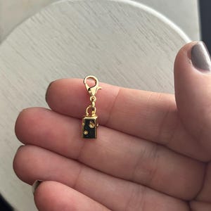 Puede incluir: Encanto de oro con una pequeña forma de cubo con agujeros, que recuerda a un trozo de queso suizo. El encanto está unido a un cierre de langosta de oro.