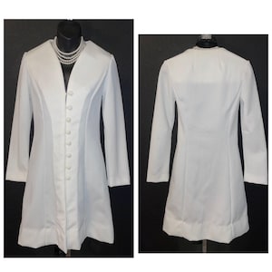 May include: A long-sleeved white coat featuring a V-neckline, a single front closure with a series of small white buttons, and a clean, structured silhouette. The garment is displayed on a mannequin, showing both the front and back views.
