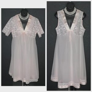 May include: Two vintage pale pink nightgowns on mannequins. One has short lace sleeves and a matching lace bodice. The other is sleeveless with a lace bodice. Both have a V-neck, a satin ribbon tie, and a lace trim at the hem.