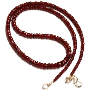May include: A long necklace made of small, faceted ruby beads. The necklace is strung on a silver chain and has a silver clasp.
