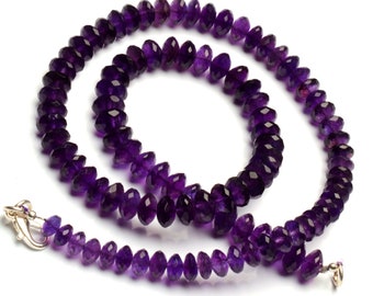 May include: A purple amethyst gemstone necklace with faceted beads. The necklace is made with a silver clasp and is approximately 18 inches long.