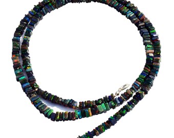 May include: A black opal necklace with a silver clasp. The necklace is made of square-shaped beads that are iridescent and have a variety of colors, including green, blue, and red.
