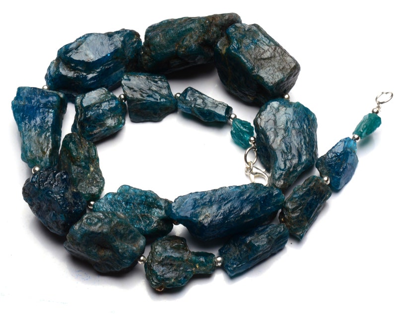 Puede incluir: Un collar hecho de piedras de apatita azul verdoso sin pulir. Las piedras son de forma y tama&ntilde;o irregulares, y est&aacute;n enhebradas en una cadena de plata.