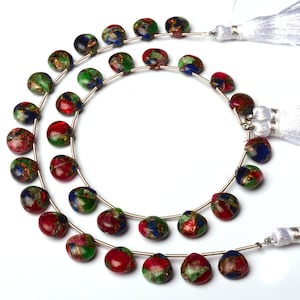 May include: A strand of multi-coloured gemstone beads with a red, green, and blue colour scheme. The beads are round and have a speckled appearance. The strand is strung on a silver wire and has two white tassels.