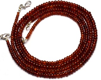May include: A long strand of brown gemstone beads with silver clasps. The beads are round and smooth, and the necklace is made of multiple strands.
