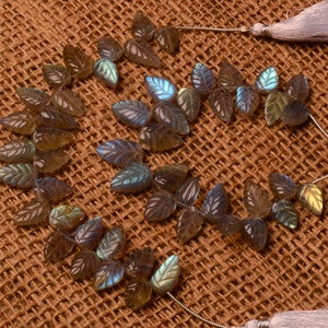 May include: A strand of iridescent labradorite gemstone beads in the shape of leaves. The beads are strung on a silver wire and have a natural, organic look.