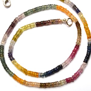 Puede incluir: Un collar de piedras preciosas multicolores con un cierre de plata. El collar est&aacute; hecho de peque&ntilde;as cuentas redondas en tonos de azul, verde, amarillo, naranja y rojo.