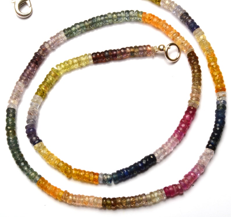 Puede incluir: Un collar de piedras preciosas multicolores con un cierre de plata. El collar est&aacute; hecho de peque&ntilde;as cuentas redondas en tonos de azul, verde, amarillo, naranja y rojo.