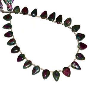 May include: A strand of green, pink, and red ruby gemstone beads. The beads are faceted and have a teardrop shape. The beads are strung on a silver wire.