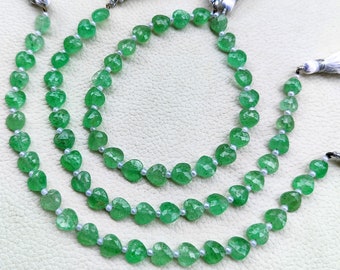 May include: Three strands of green heart-shaped gemstone beads with white tassels.
