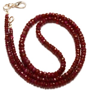 May include: A double strand necklace made of red ruby beads. The beads are faceted and have a slightly irregular shape. The necklace is finished with a gold clasp.