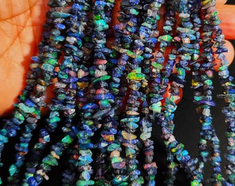 May include: A strand of blue, green, and purple opal chip beads. The chips are irregular in shape and size, and have a shimmering, iridescent finish.