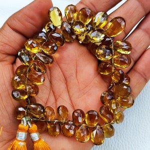 May include: A strand of faceted, teardrop-shaped, golden brown gemstone beads. The beads are strung on a thin cord and have a tassel at the end.