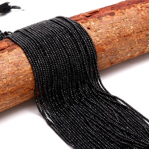 Peut inclure: Un brin de perles de pierres précieuses facettées noires. Les perles sont petites et de taille uniforme, et elles sont enfilées sur un fil transparent. Les perles sont disposées en un motif lâche et fluide.