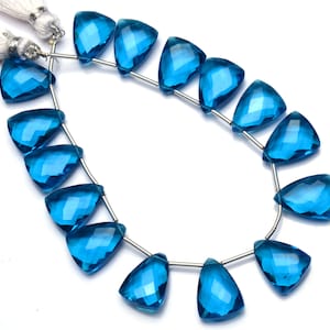 May include: A strand of blue topaz gemstone beads, each bead is faceted and shaped like a teardrop. The beads are strung on a silver wire and are ready to be made into jewelry.